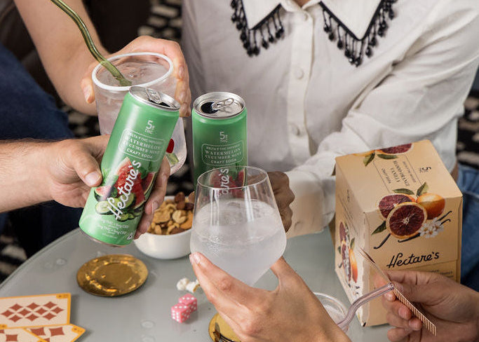 People enjoying Hectare's Watermelon Cucumber Mint Delta 9 Craft Sodas at a table playing cards. 